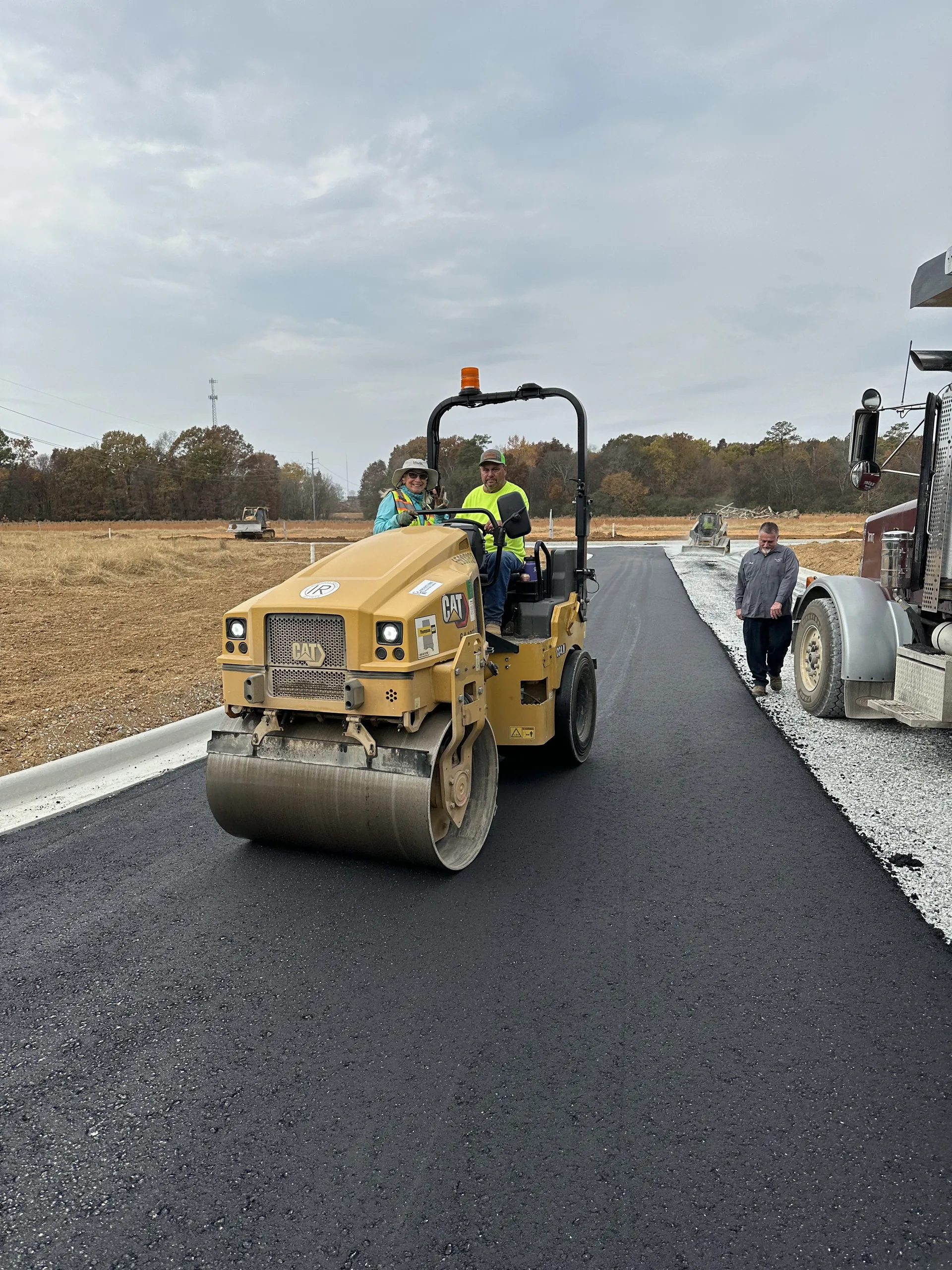 Project One Contracting operator running a CAT tandem roller to compact a freshly paved asphalt drive in North Alabama
