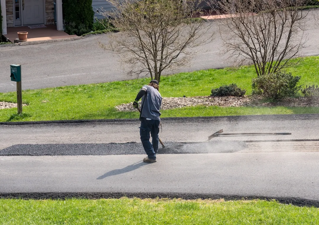 Crew placing hot-mix asphalt patch on a commercial lot