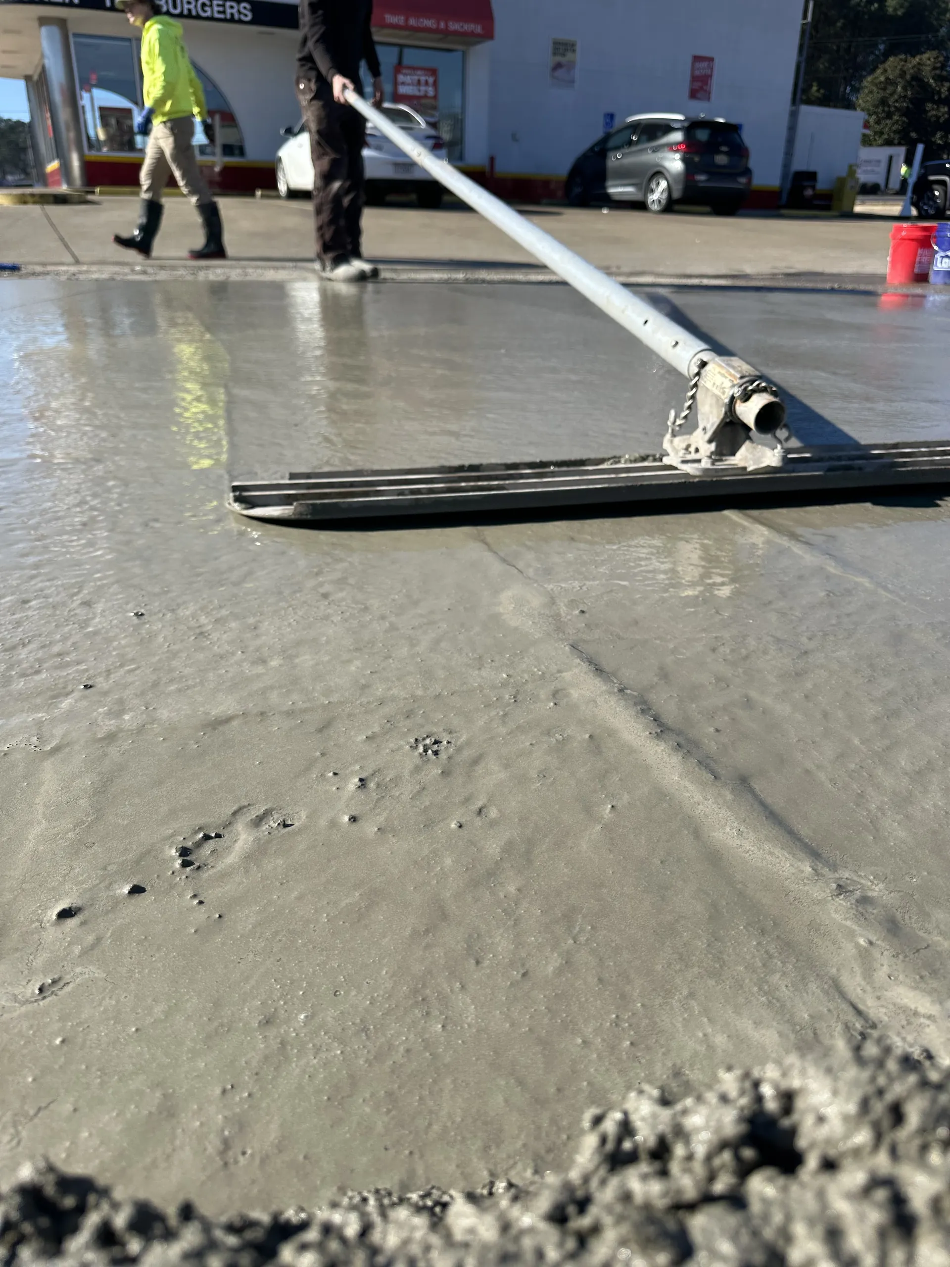 Crew bull-floating a freshly poured concrete pad at a restaurant