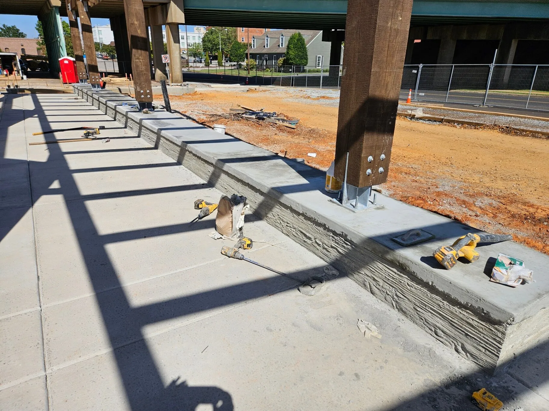 Formed and finished concrete curb running along a commercial sitework project under a bridge overpass