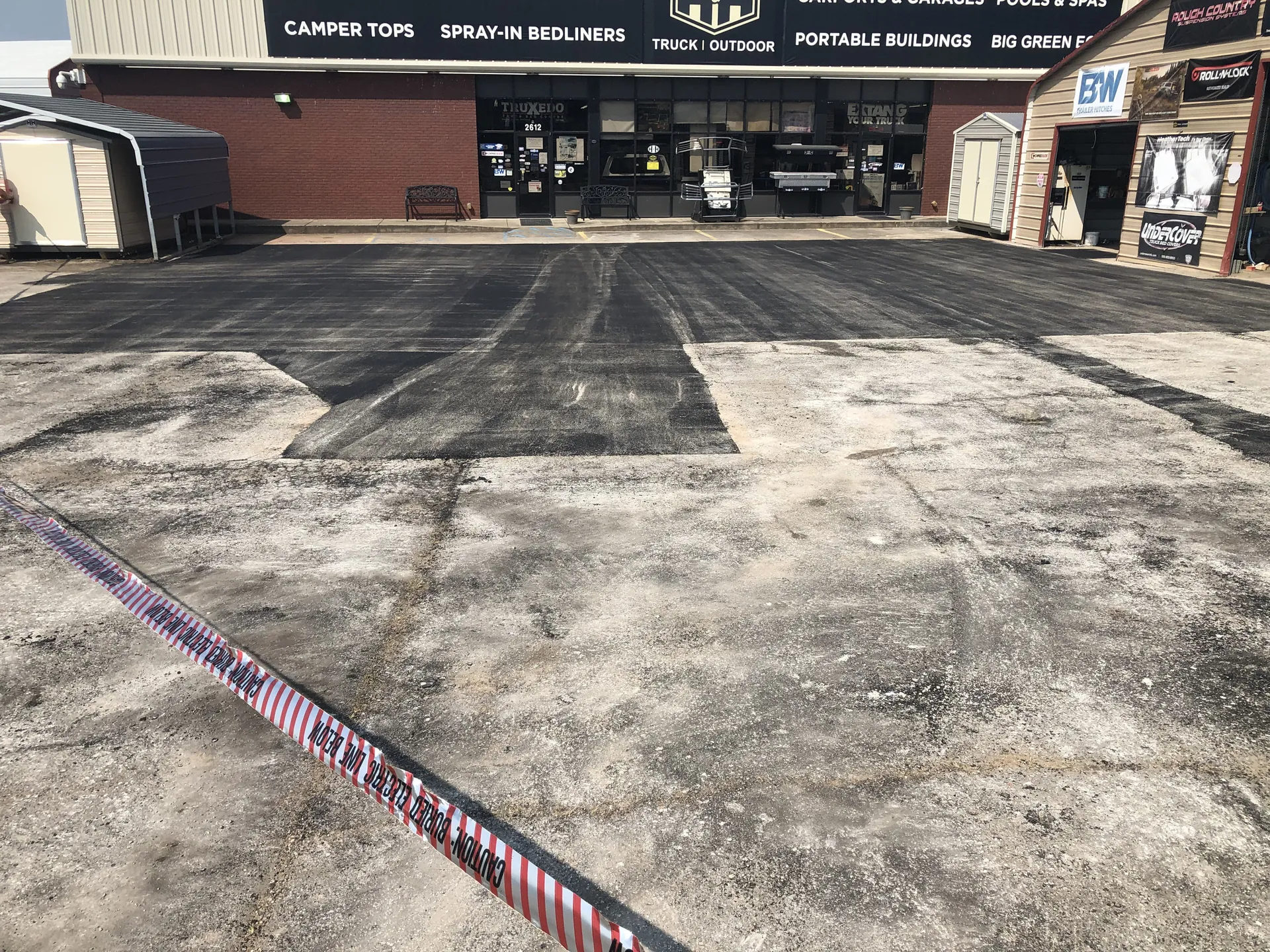 Asphalt patch repair fronting a commercial storefront parking lot