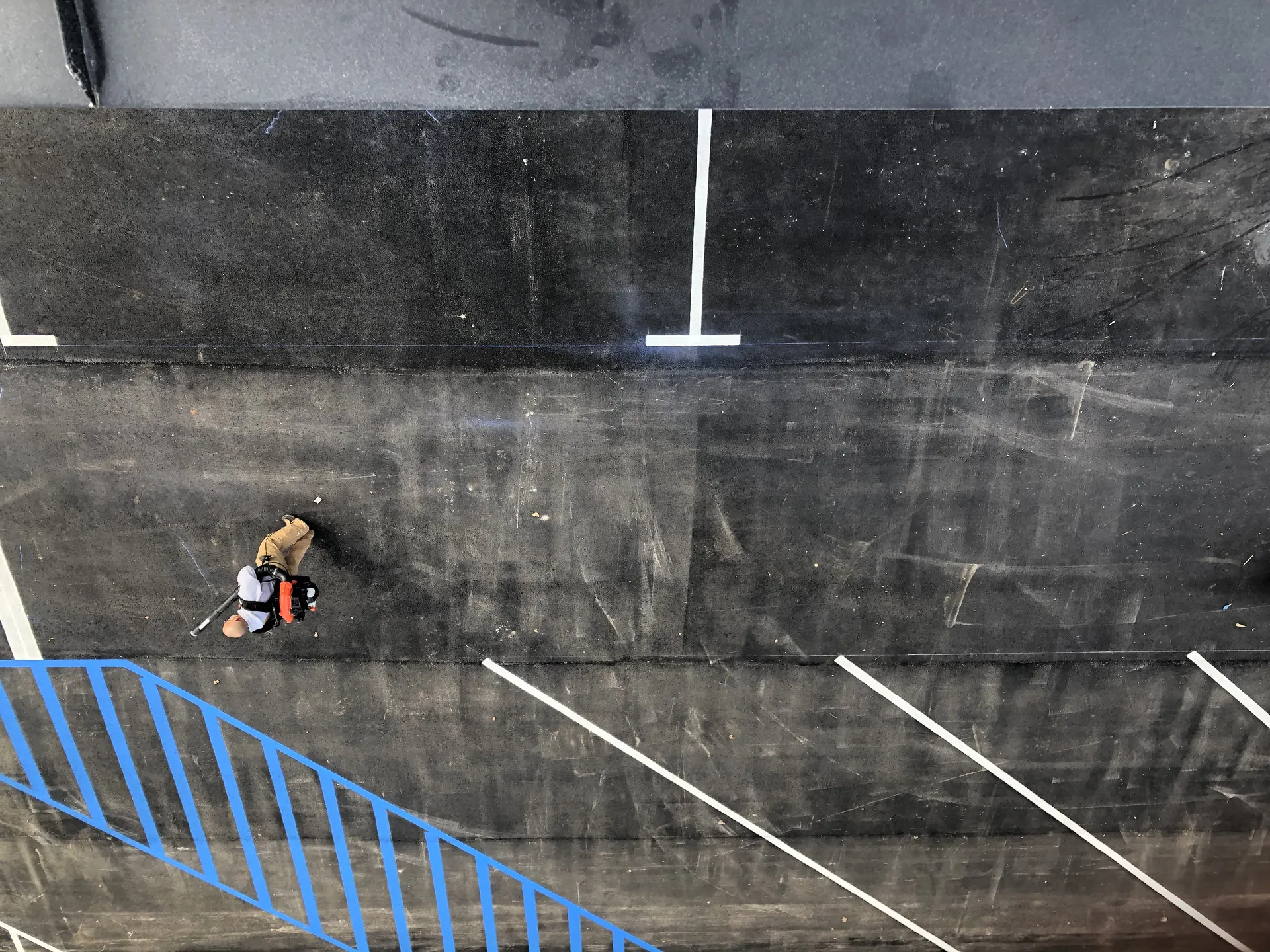 Aerial view of Project One crew prepping a parking lot surface with a backpack blower before striping